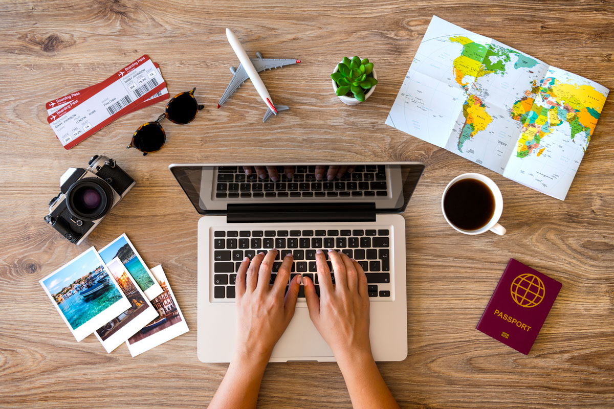 laptop surrounded by travel items such as a map, model aeroplane, and passport to illustrate the biggest seo mistakes bloggers make